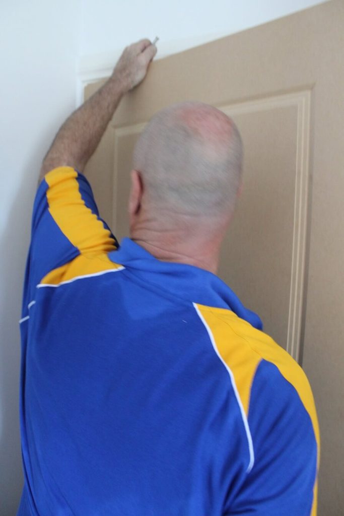 carpenter lining up internal door to begin hanging internal door