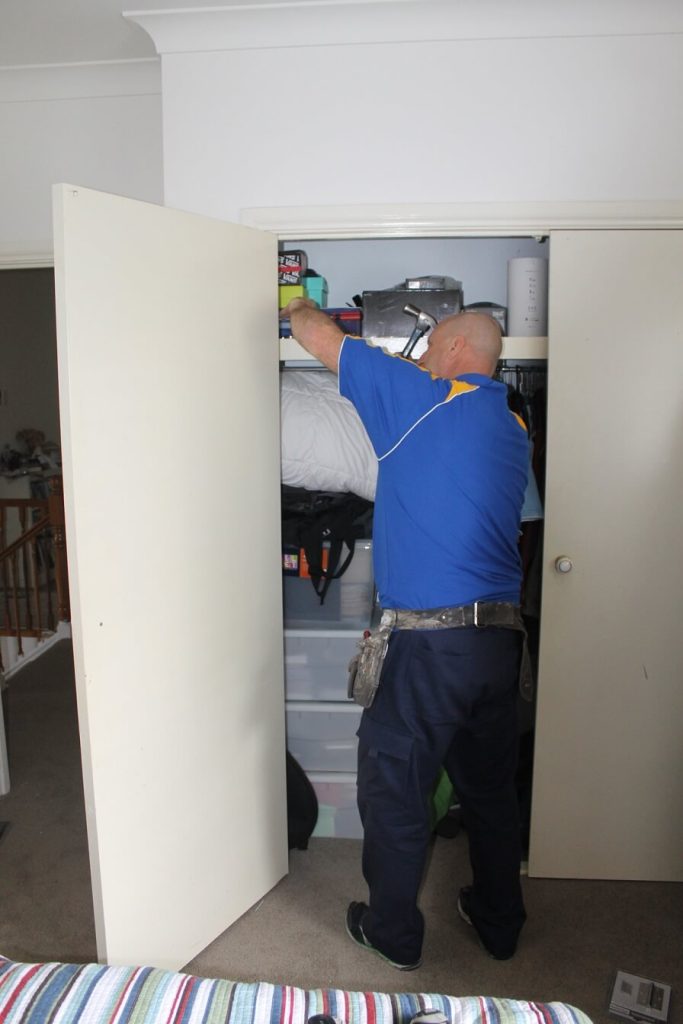 carpenter holding and removing internal door leaning in and using drill