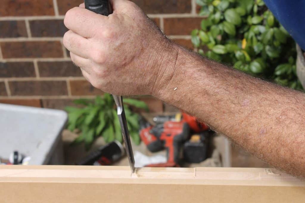 chisel held to internal door to make cut out for hinges